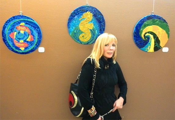 Avtorica Vlasta Cah Žerovnik s tremi izmed razstavljenih slik v Mariboru